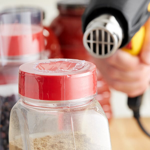 A clear plastic container with a 2" clear perforated shrink band on the lid.