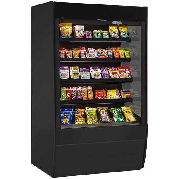 A black Federal Industries non-refrigerated display case with different types of snacks on shelves.