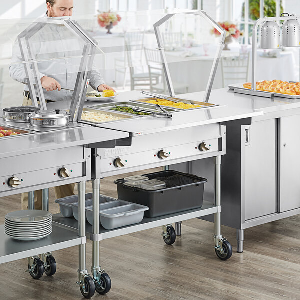 A man using a ServIt electric steam table to prepare food outdoors.