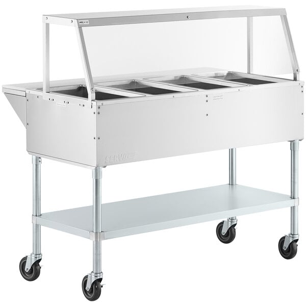 A ServIt stainless steel electric steam table on wheels with angled glass sneeze guard.