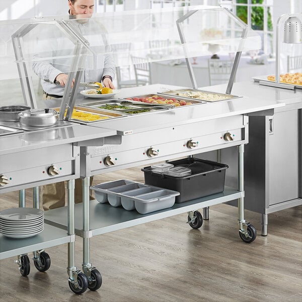 A man standing in front of a ServIt steam table with trays.