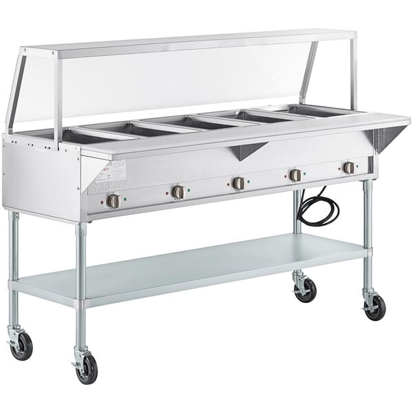 A ServIt open well electric steam table on wheels with an angled sneeze guard.
