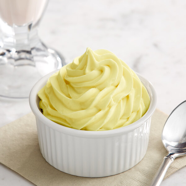 A bowl of yellow ice cream with a spoon next to it.