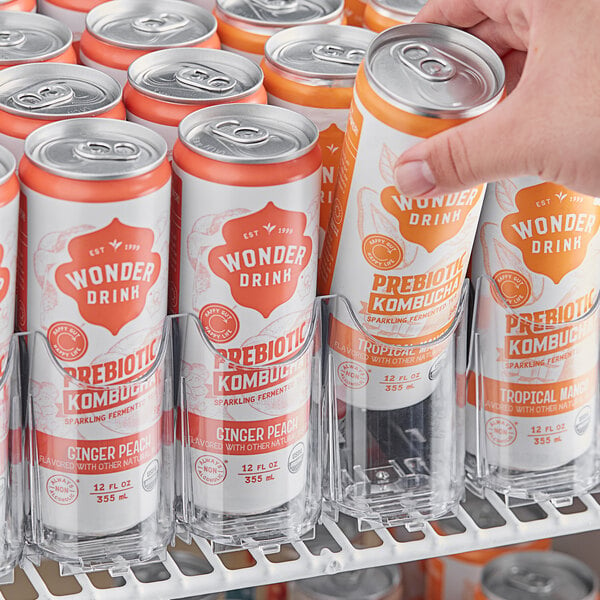 A hand using a Beverage-Air lane organizer to dispense a can of soda.