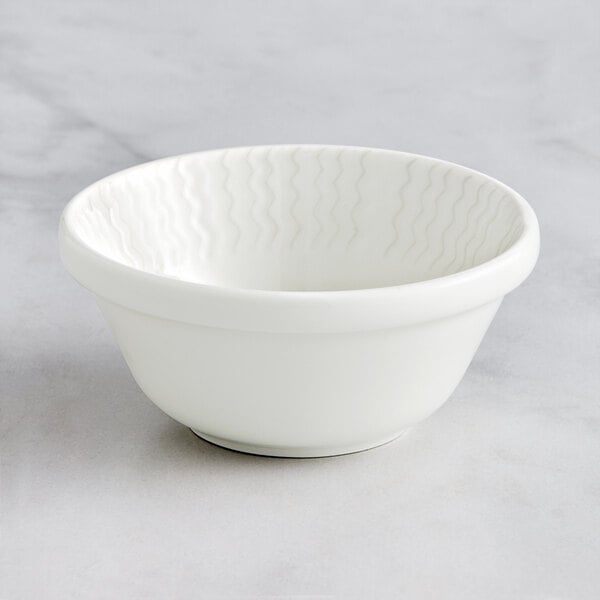 A close-up of a RAK Porcelain ivory bowl with wavy lines on it.