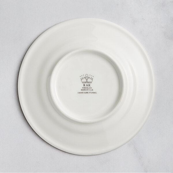 A white RAK Porcelain flat plate with an embossed crown logo on the rim.