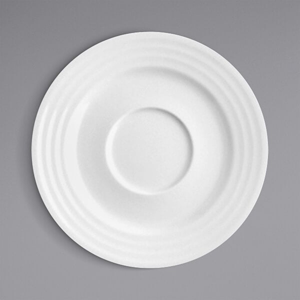 A white RAK Porcelain saucer with a circular embossed design.