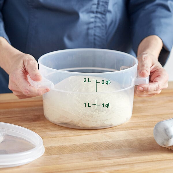 A person holding a Vigor translucent plastic container with white dough inside.