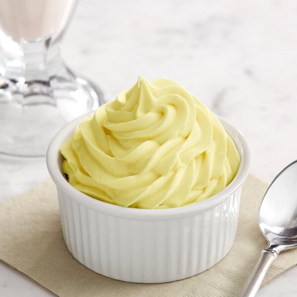 A bowl of Creamery Ave. Pineapple soft serve ice cream with a spoon in it.