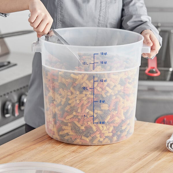 A woman holding a large Vigor translucent plastic container filled with pasta.