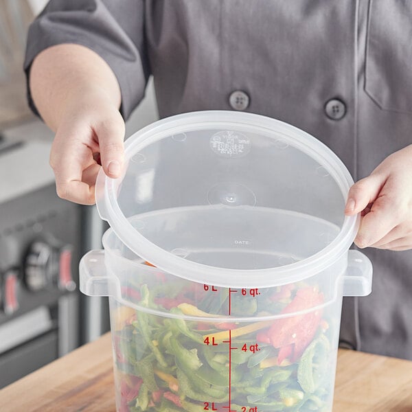 A person holding a Vigor translucent plastic container with food in it and a lid.