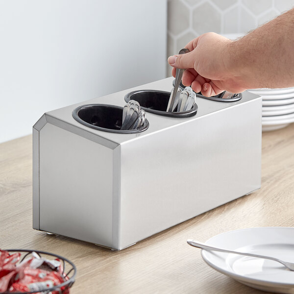 A silver container holding utensils including a spoon.