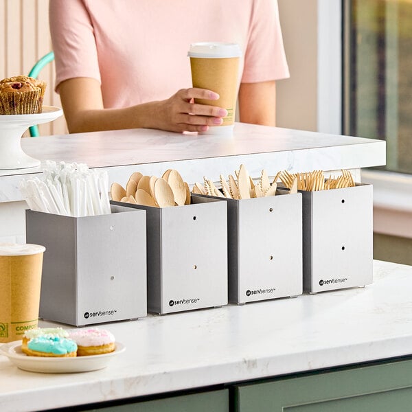 A set of four stainless steel countertop or wall-mount organizers for flatware and straws.