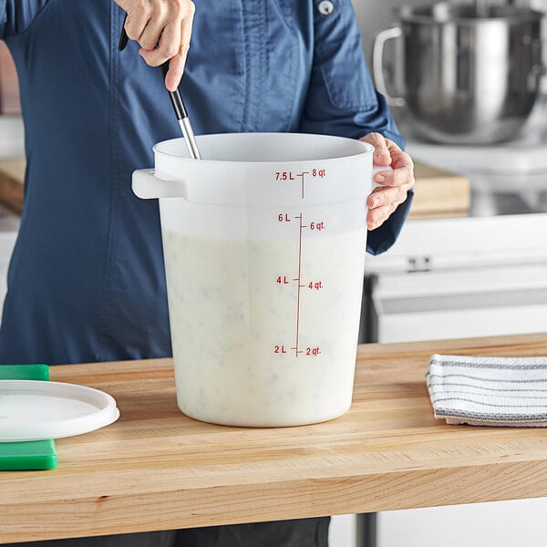 A person mixing liquid in a large white Vigor food storage container.