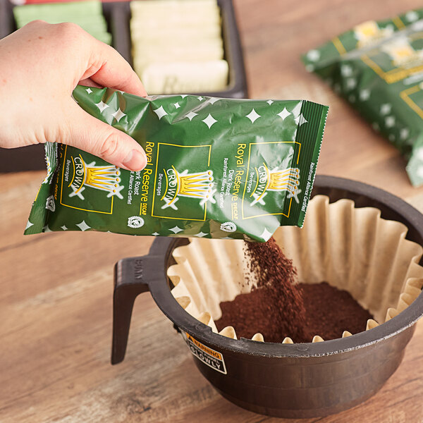 A hand pouring Crown Beverages Royal Reserve Sumatra Decaf Coffee into a coffee filter.