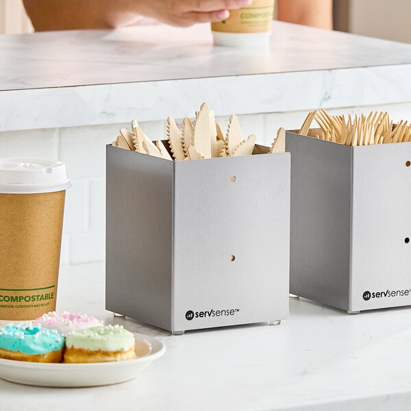 A stainless steel countertop or wall-mount organizer holding flatware and straws.