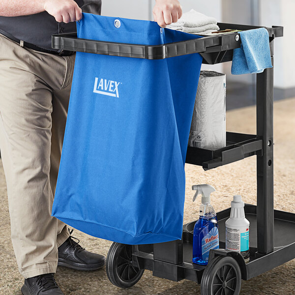 A man putting a blue Lavex janitor cart bag into a cart.