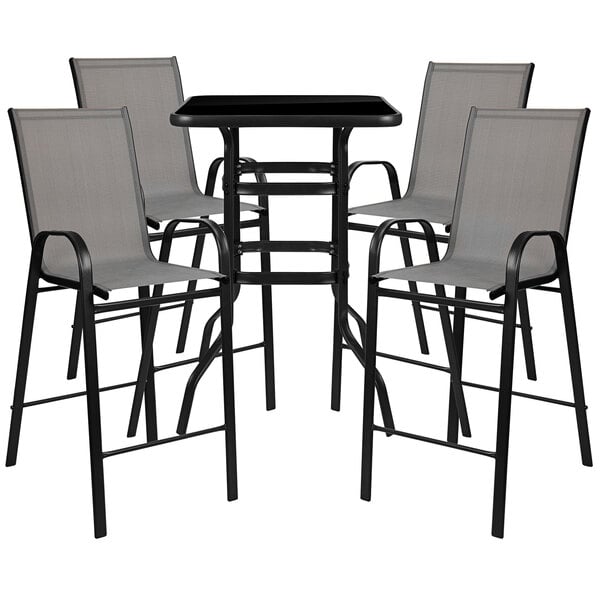 A Flash Furniture outdoor bar table with gray chairs on an outdoor patio.