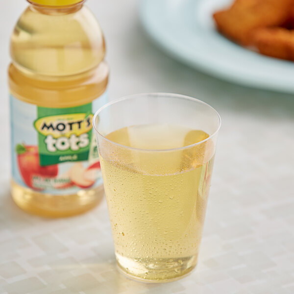 A glass of apple juice next to a bottle of Mott's For Tots Apple Juice.