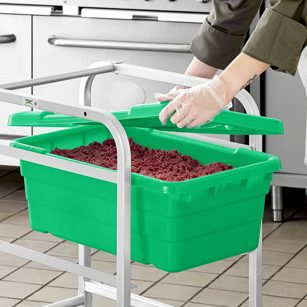 A person putting red berries in a green Choice meat lug with cover.