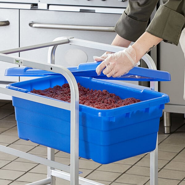 A person in gloves is putting food into a blue Choice meat lug with a cover.
