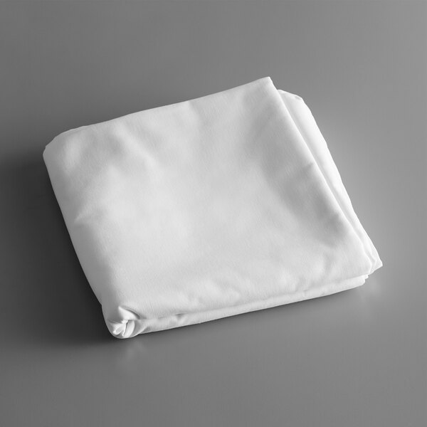 A folded white tablecloth on a gray surface.