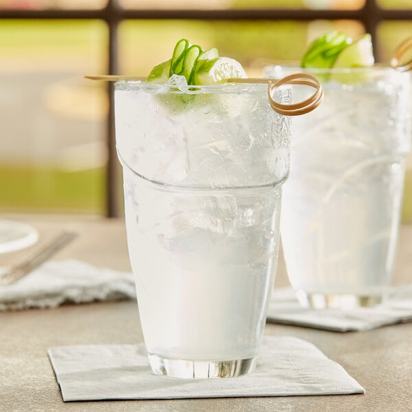 Two glasses of water with ice on a table.