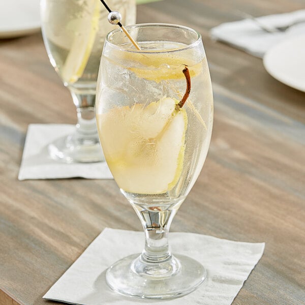 A glass of water with Pure Craft Beverages Ginger Pear Beverage Concentrate in it and a stick.