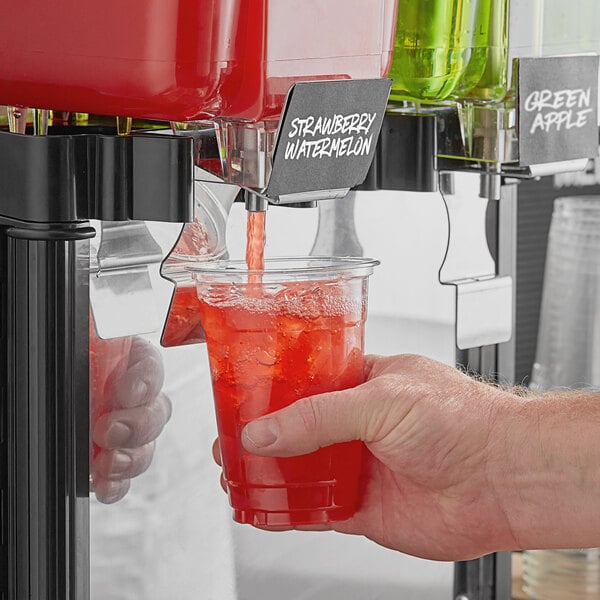 A hand holding a glass of red Pure Craft Beverages Strawberry Watermelon beverage.