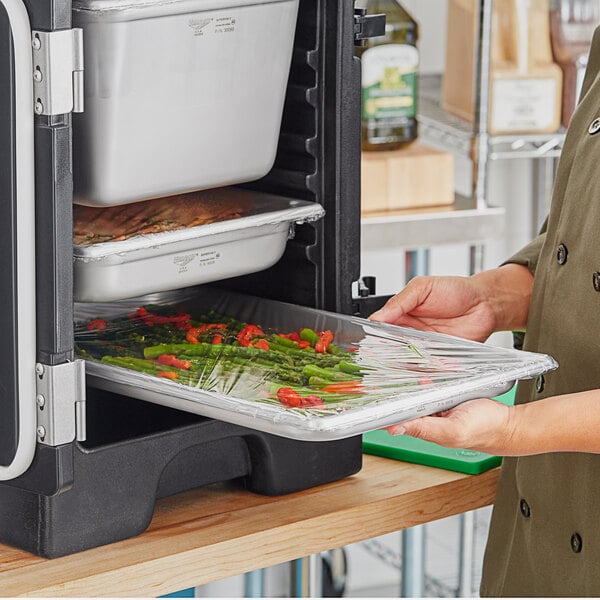 A woman holding a Vollrath stainless steel tray of food.