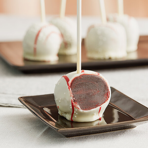 An individually wrapped red velvet cake pop on a stick.
