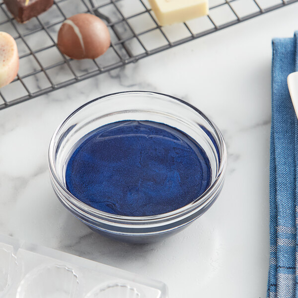 A bowl of blue cocoa butter on a counter next to a cooling rack.