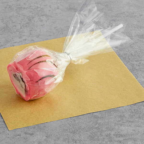 A pink frosted chocolate cake pop in a plastic wrapper.