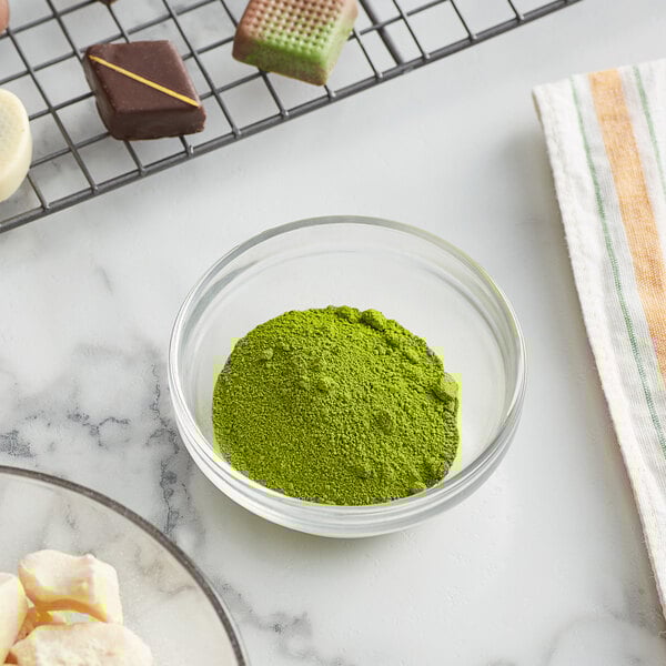 A bowl of Roxy & Rich light green fat dispersible powder next to a plate of chocolates.
