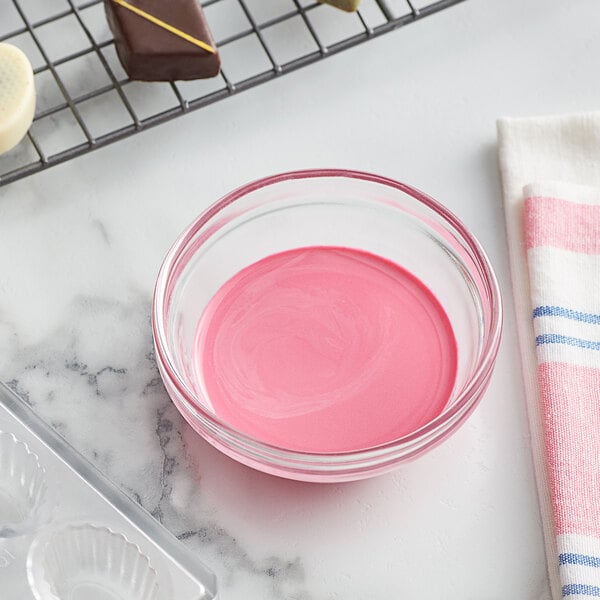 A bowl of pink liquid next to a silicone mold.