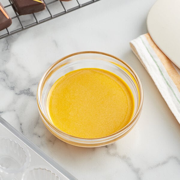 a bowl of yellow liquid next to a tray of chocolates