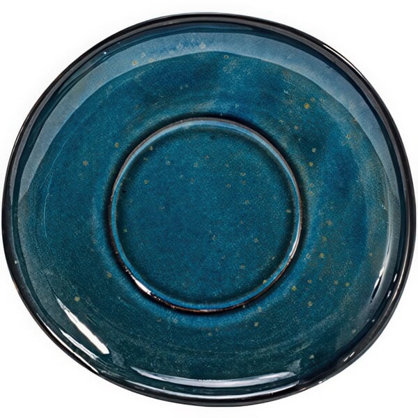 A close-up of a blue Front of the House Artefact porcelain saucer with a round rim.