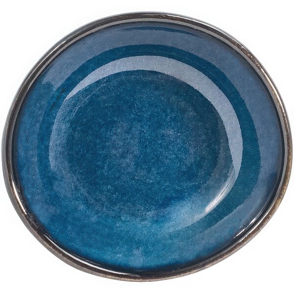 An indigo porcelain ramekin with a rim on a table.