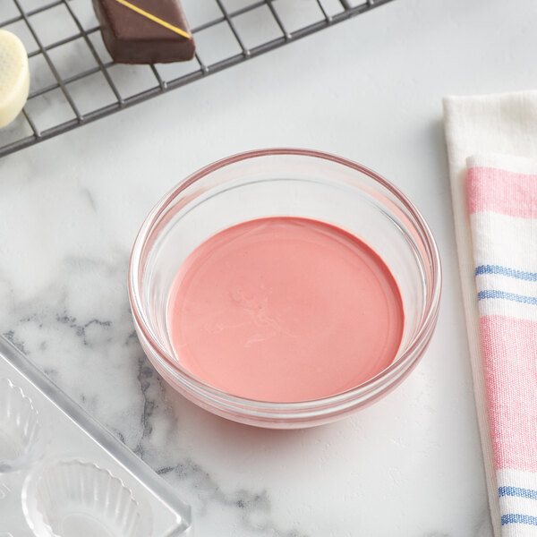 A bowl of pink liquid next to a baking tray.