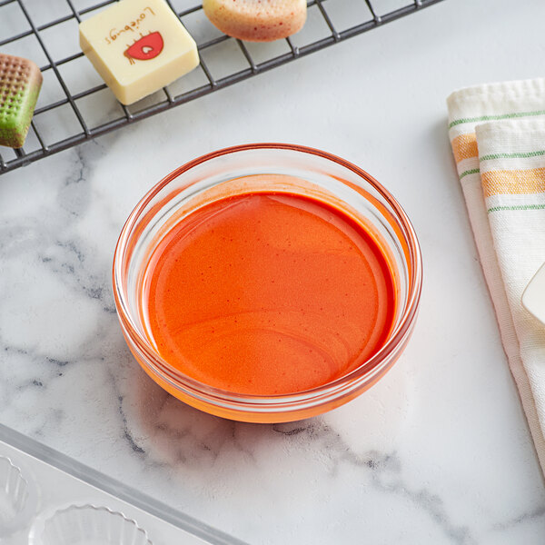 A bowl of orange liquid next to a baking rack.