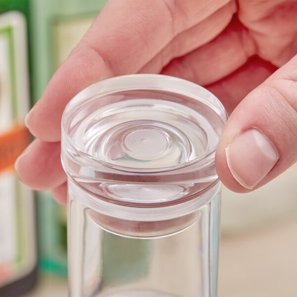 A person using an American Metalcraft cap to hold a glass of clear water.