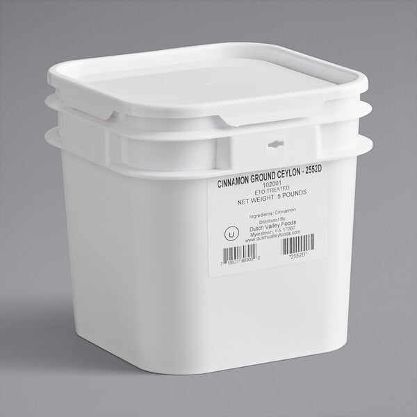 A white plastic container of Ground Ceylon Cinnamon with a label on it.