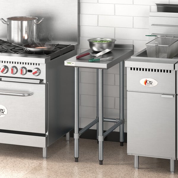 A Regency stainless steel filler table in a professional kitchen with a stove and pots.