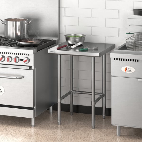 A Regency stainless steel open base work table in a professional kitchen with stainless steel stoves and a sink.