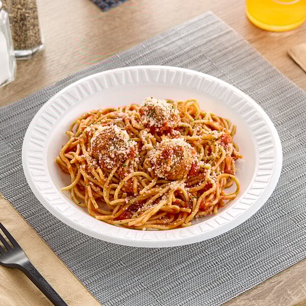 A Dart Concorde white foam plate with spaghetti and meatballs on it.