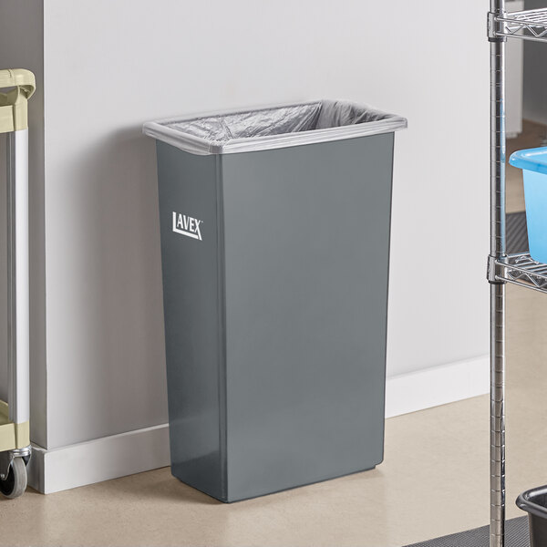 A Lavex gray rectangular trash can on a shelf with a bag inside.