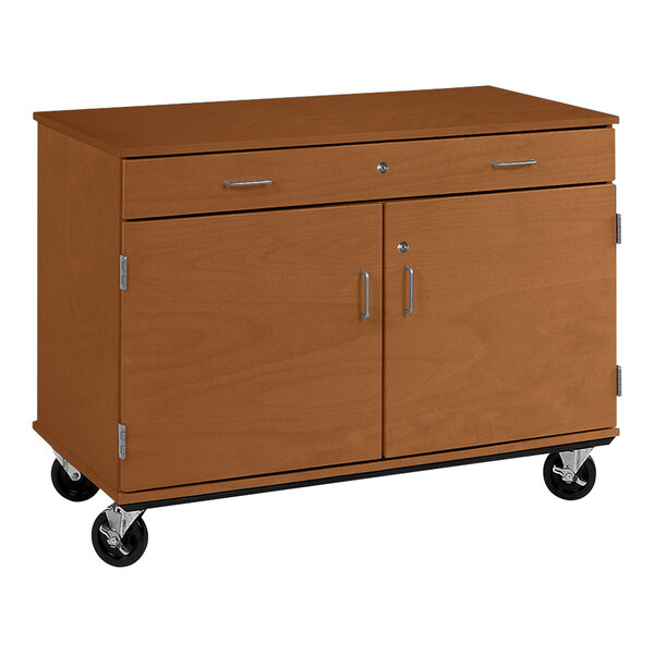A brown wooden cabinet with black wheels and two doors and two drawers.
