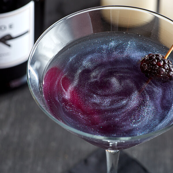 A glass of purple cocktail with a blackberry garnish.