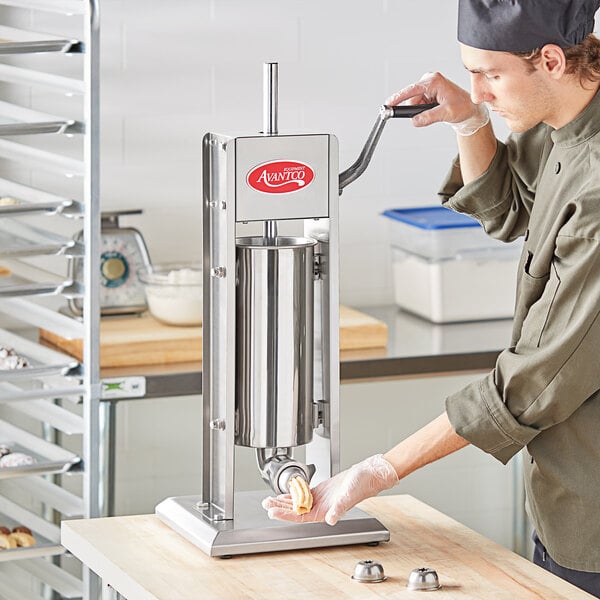 A man using an Avantco stainless steel vertical churro stuffer to make churros.