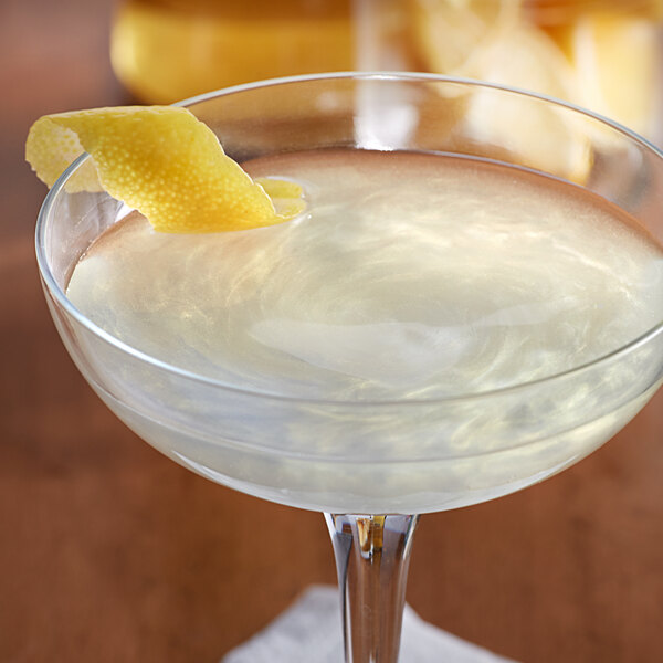 A glass of Spirdust Gold Pearl cocktail shimmer with a lemon peel on the rim.